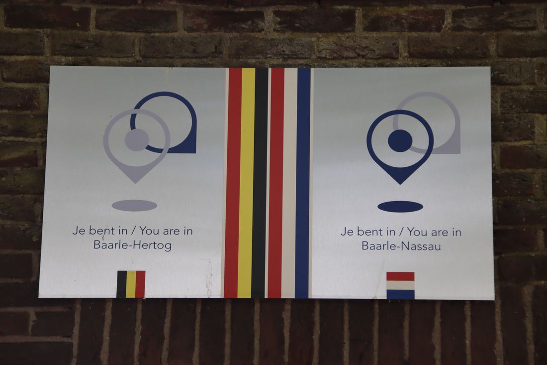 Two plaques on a wall in Baarle telling visitors which country they are in
