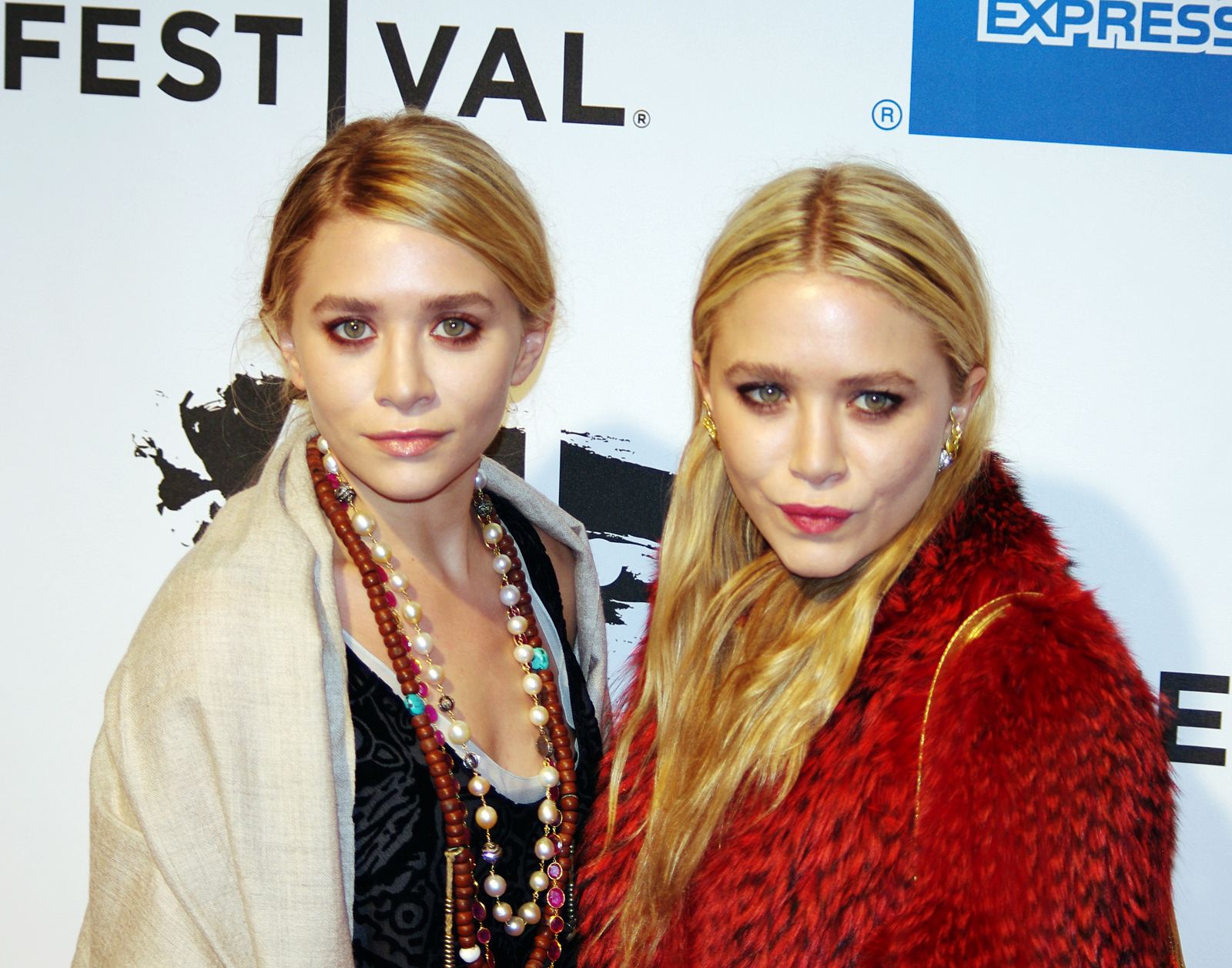 Ashley and Mary-Kate Olsen standing side by side in dark outfits at a film premiere