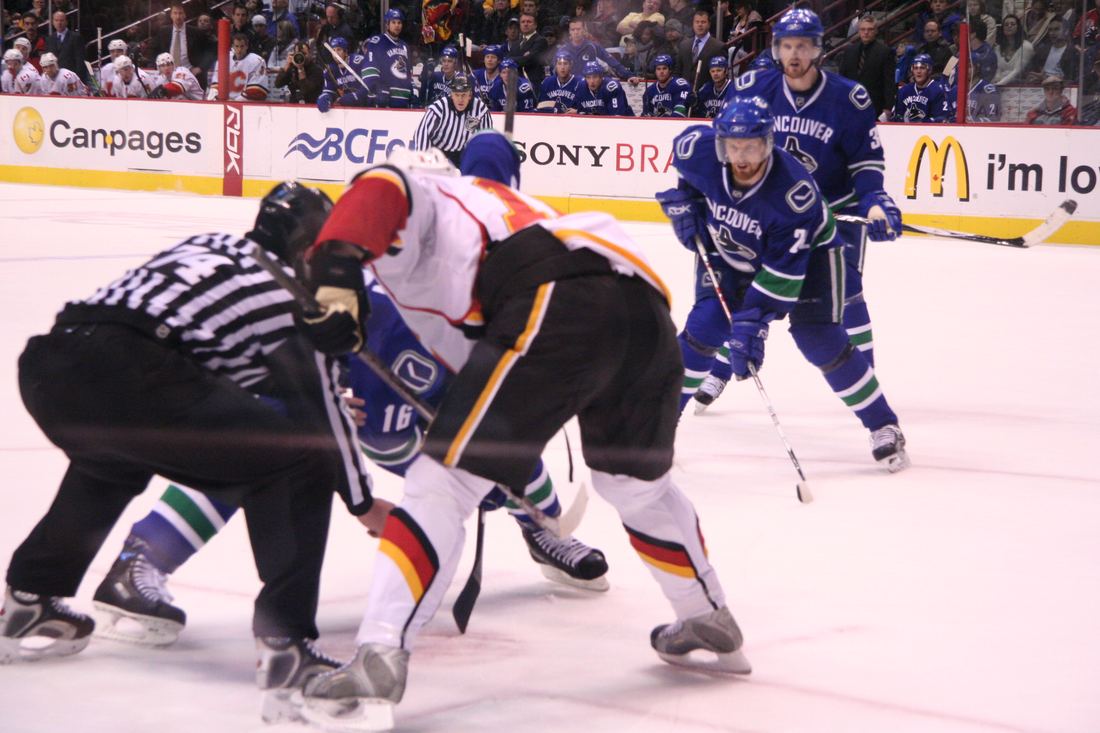 Daniel and Henrik Sedin in white Vancouver Canucks jerseys on the ice during an NHL game
