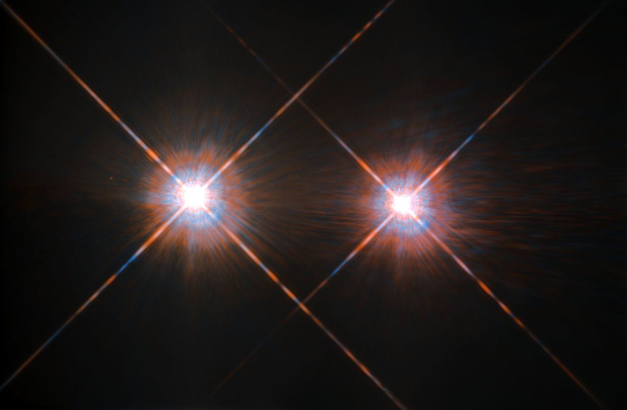 Two brilliant white stars side by side against black space, each crossed by long diffraction spikes, like a pair of matching headlamps