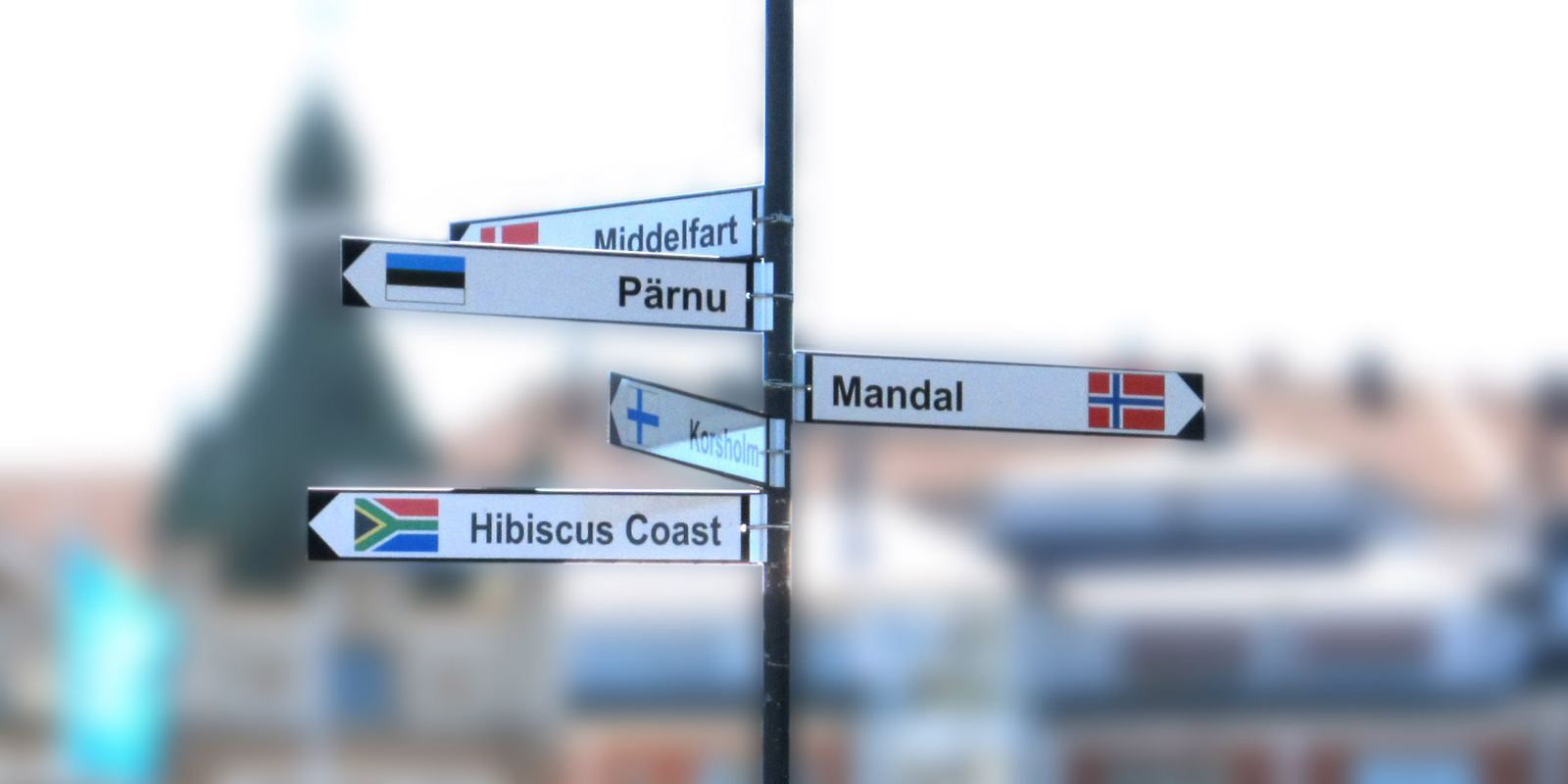 A signpost in Oskarshamn, Sweden, pointing to its twin towns with their flags