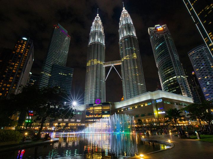 The Petronas Twin Towers in Kuala Lumpur glowing silver against a dark night sky, joined by a skybridge